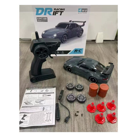 QC-bild med den grå driftbilen, pistolgreppskontrollen, 4 extra däck, 5 koner och 2 tunnor upplagda framför förpackningen.